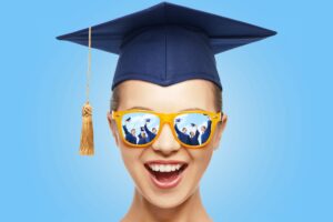 graduation, education, school and people concept - happy screaming teenage girl in shades and mortarboard or bachelor hat over blue background
