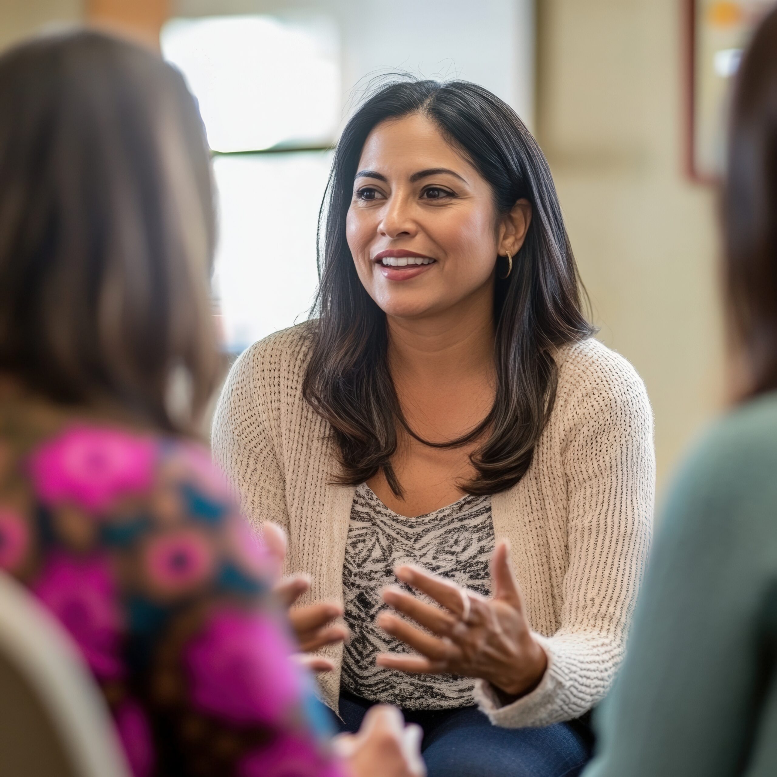 Hispanic woman mentoring small group of women in community center during personal growth discussion emphasizing empowerment support and women's development leadership