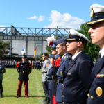 Soldaten in bunten Uniformen stehen im Karree vor einer angetretenen Paradeaufstellung.