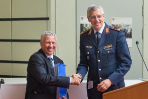 Ein Mann in der Uniform eines Luftwaffengenerals schüttelt einem Mann im Anzug die Hand.