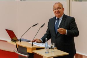 Ein circa 53 Jahre alter Mann mit Brille hinter einem Rednerpult.