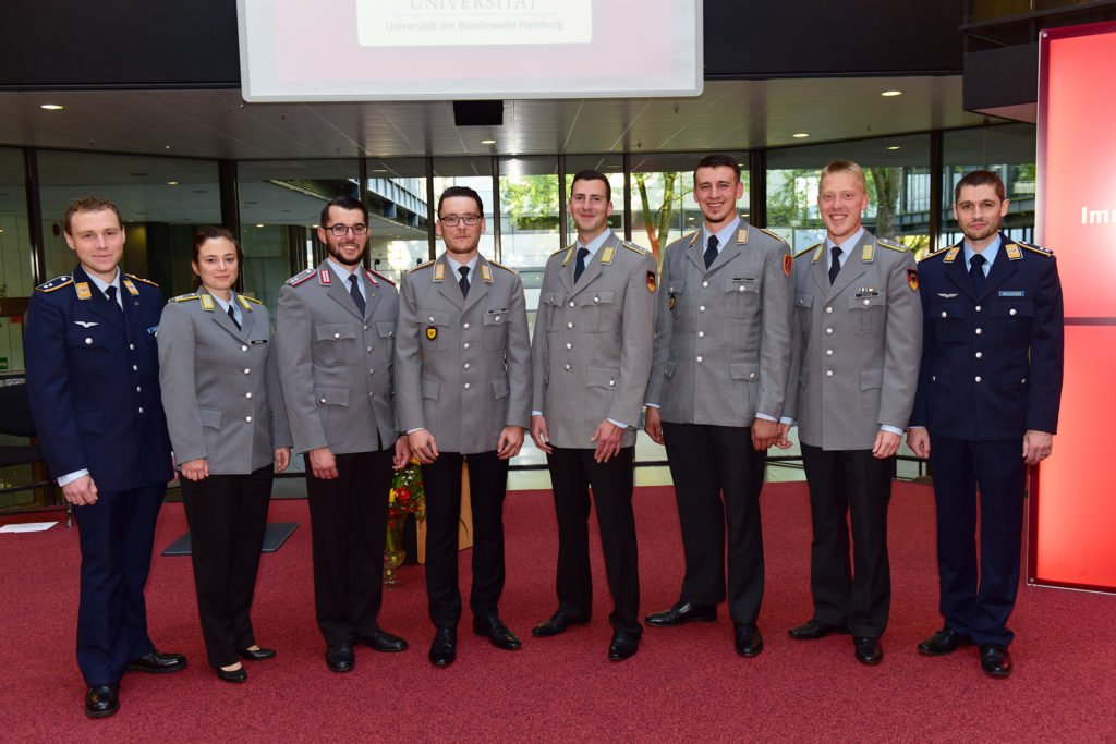 Eine Reihe augenscheinlich glücklicher Menschen in Uniform, auf einem roten Teppich stehend.