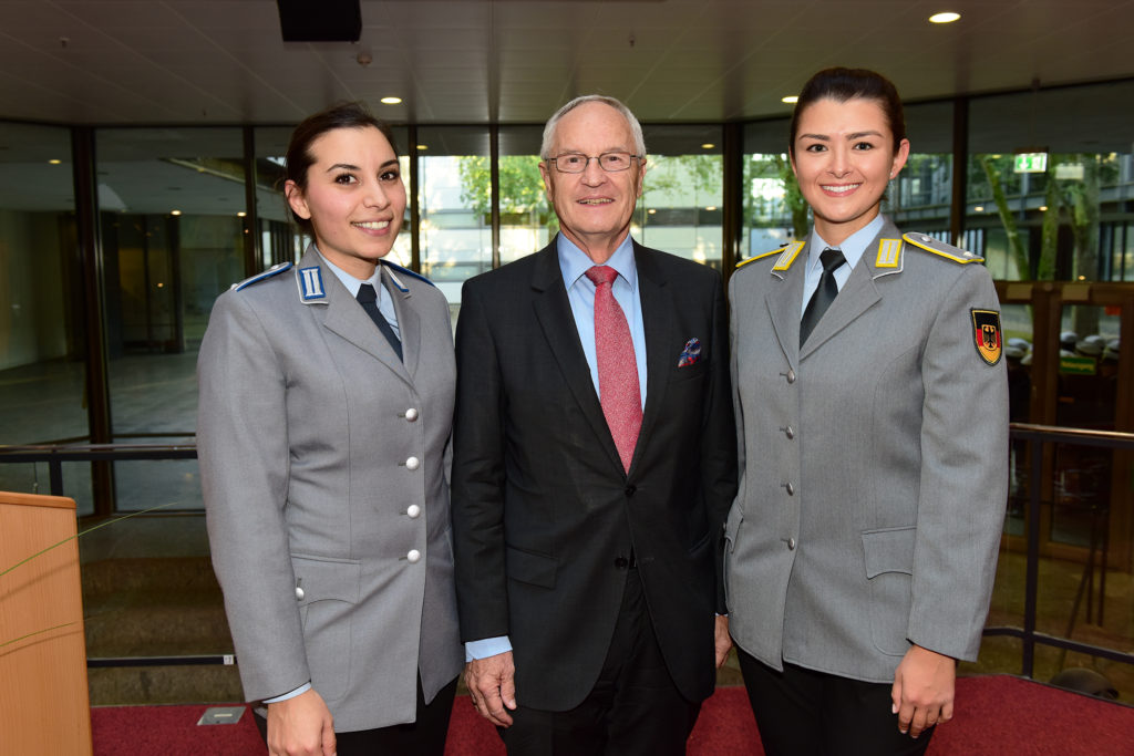 Zwei junge Frauen in Heeresuniform und ein älterer Herr im Anzug.
