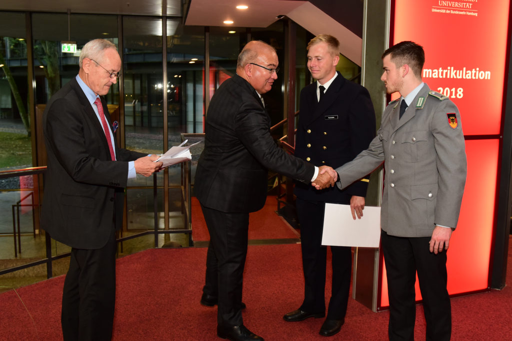 Zwei ältere Herren im Anzug und zwei junge Offiziere in Uniform.