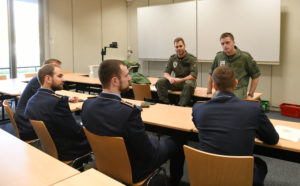 Soldaten in Uniform sprechen mit anderen Soldaten, die eine Fliegerkombi tragen.