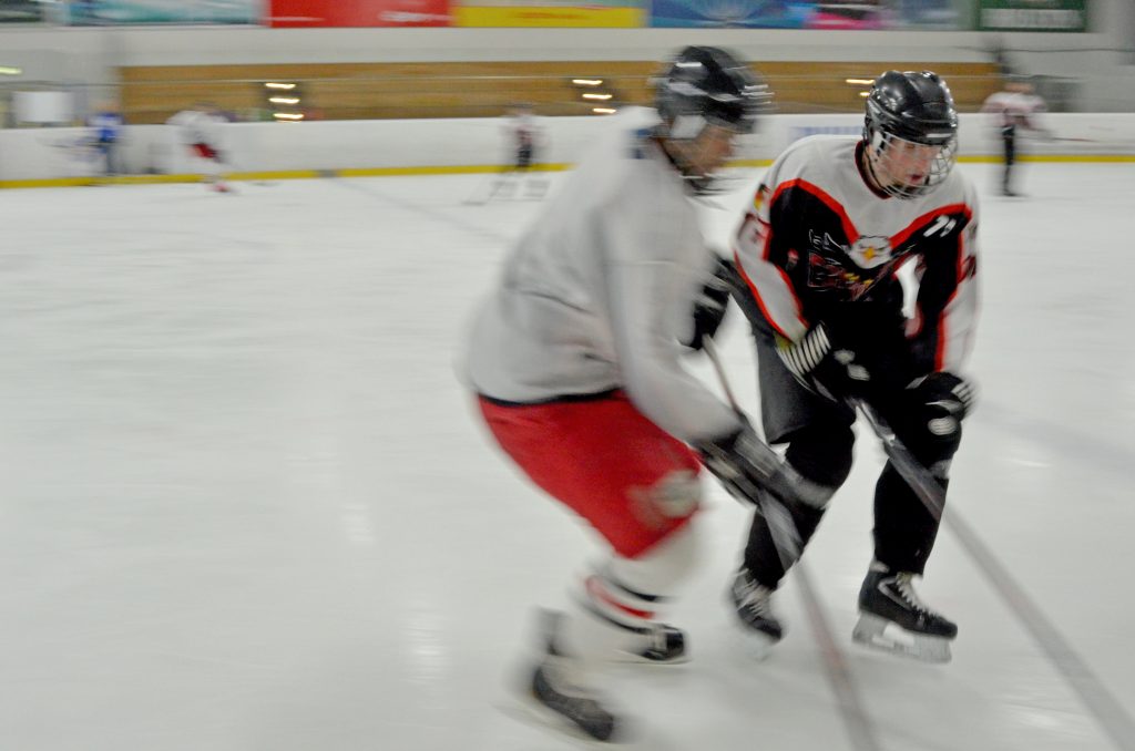 Zwei Eishockeyspieler kämpfen um einen Puck.