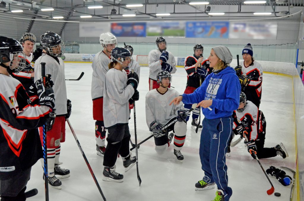 Eishockeyspieler stehen im Kreis um die Trainerin.