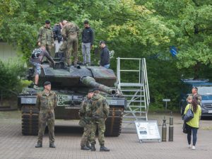 Soldaten stehen auf und vor einem Kampfpanzer