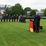 Ein Mann hinter einem Rednerpult steht vor eine Quarree aus angetretenen Soldaten