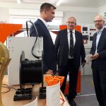 Drei Männer in einem Raum voller 3D-Drucker