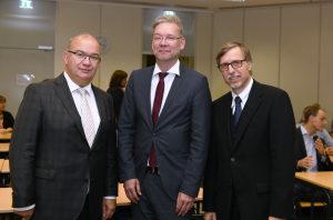 Drei Männer in dunklen Anzügen.