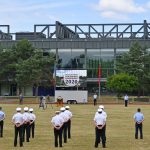 Panoramablick über eine größere Zahl von Soldaten, die auf einer Rasenfläche vor einem markanten gebäude (es ist die Mensa der HSU) angetreten stehen.