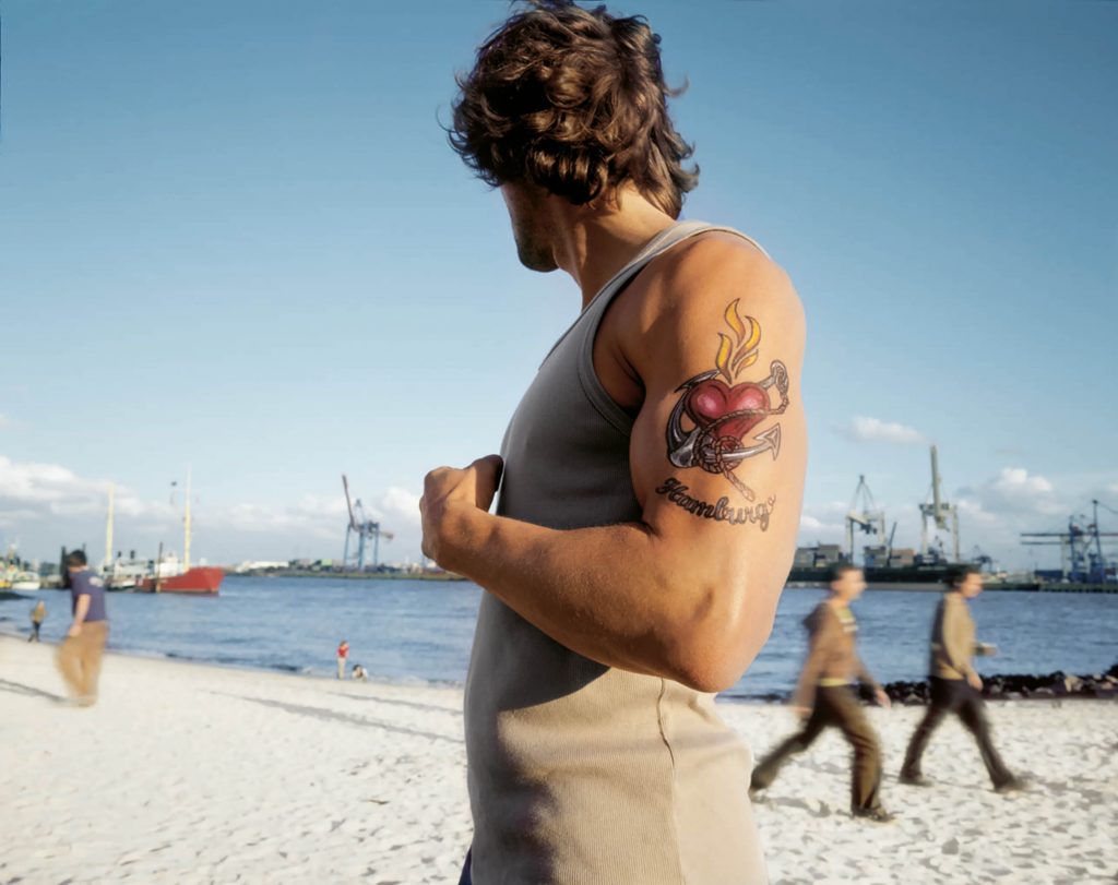 Ein Mann mit einem tätowierten Oberarm am Elbstrand