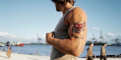 Ein Mann mit einem tätowierten Oberarm am Elbstrand