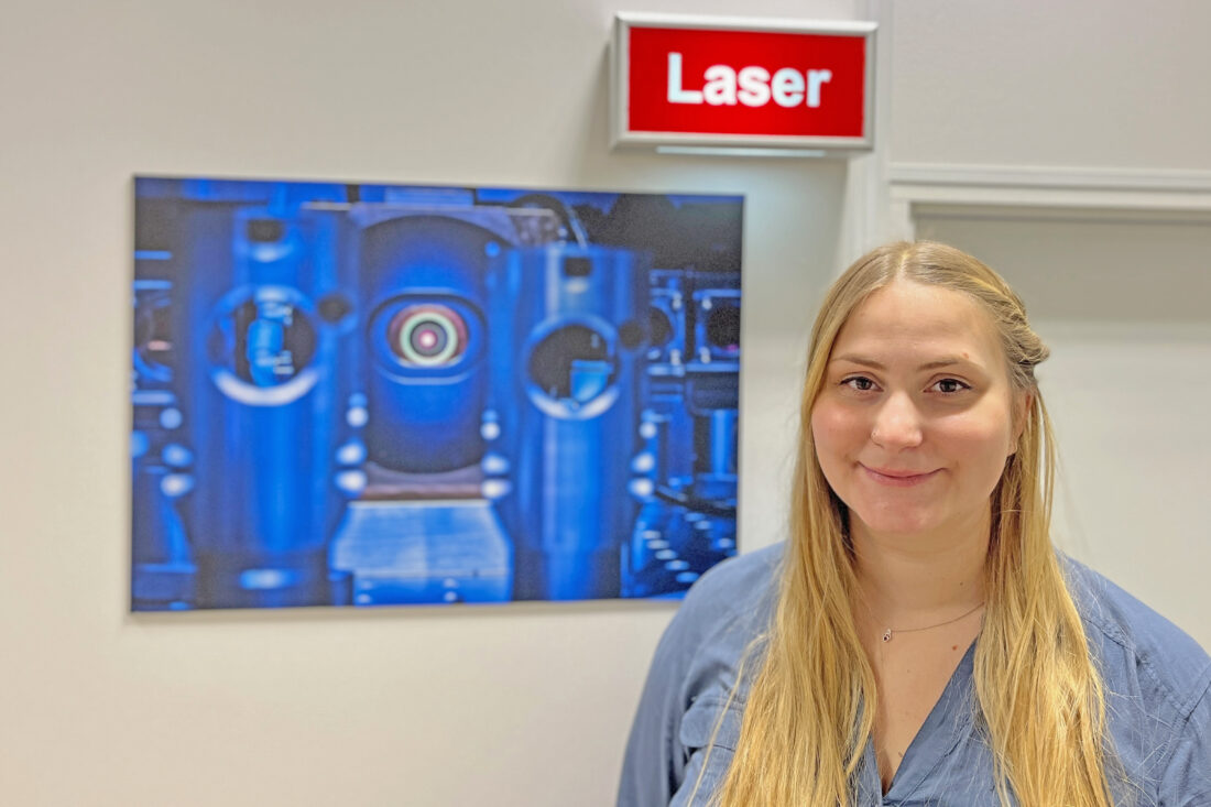 Eine junge Frau vor einer Warnleuchte mit der Aufschrift Laser