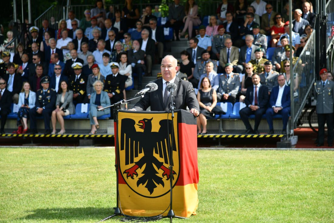 Ein Mann hinter einem Rednerpult, das in eine Bundesdienstflagge eingewickelt ist.