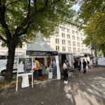 Passanten flanieren vor einem Messestand des New Production Institute anlässlich des Tages der Deutschen Einheit in Hamburg.