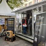 Passanten betrachten einen Messestand des New Production Institute anlässlich des Tages der Deutschen Einheit in Hamburg.