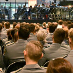 Blick von hinten aufs Podium über die Reihen sitzender, junger, uniformierter Soldatinnen und Soldaten bei der Immatrikulationsfeier 2023.