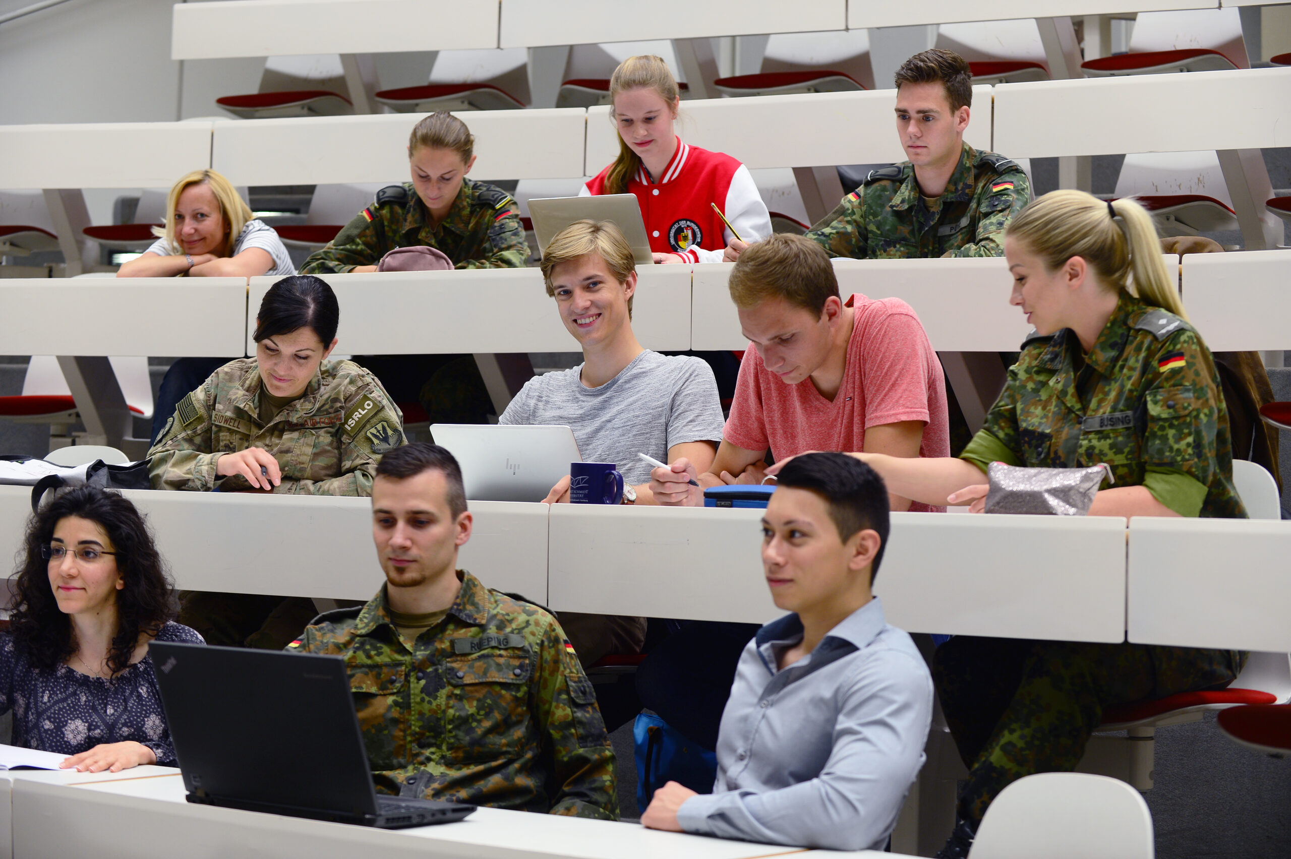 Eine Gruppe von Studierenden der Helmut-Schmidt-Universität/Universität der Bundeswehr Hamburg sitzen in einem Hörsaal und tauschen sich untereinander aus.