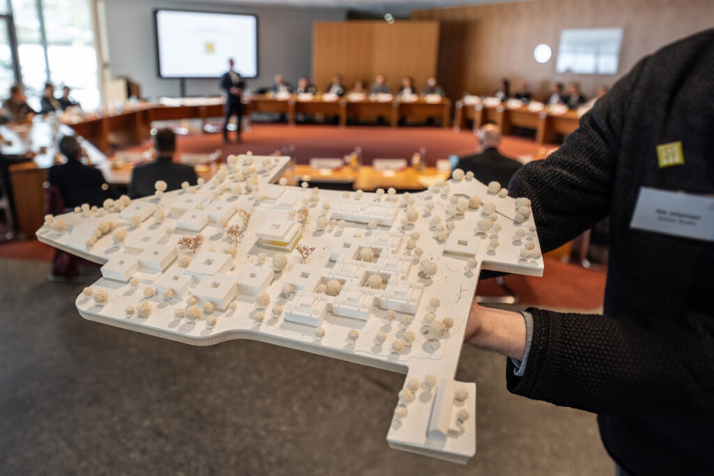Person hält ein Modell des neuen Universitätscampus in den Händen.