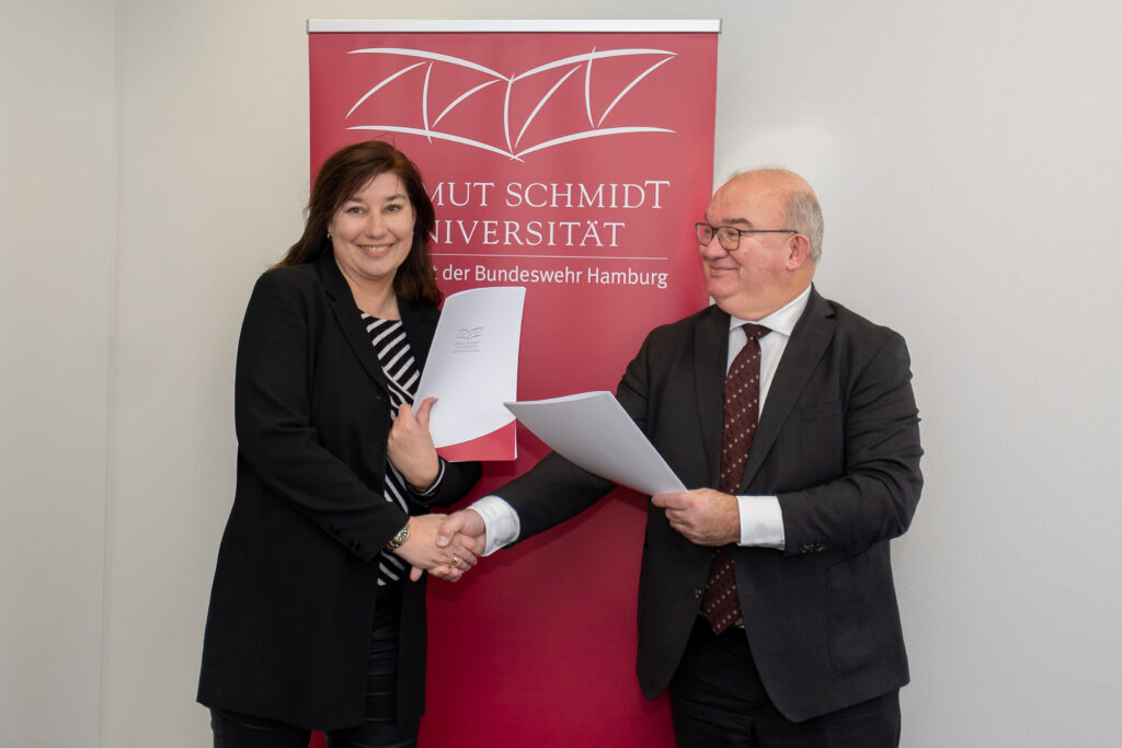 Manja Biel Hauptgeschäftsführerin des Bauindustrieverbandes Hamburg Schleswig-Holstein e.V., und Prof. Dr. Klaus Beckmann, Präsident der Helmut-Schmidt-Universität/Universität der Bundeswehr (HSU/UniBw H) schütteln sich die Hände nach der Vertragsunterzeichnung.
