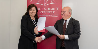 Manja Biel Hauptgeschäftsführerin des Bauindustrieverbandes Hamburg Schleswig-Holstein e.V., und Prof. Dr. Klaus Beckmann, Präsident der Helmut-Schmidt-Universität/Universität der Bundeswehr (HSU/UniBw H) schütteln sich die Hände nach der Vertragsunterzeichnung.