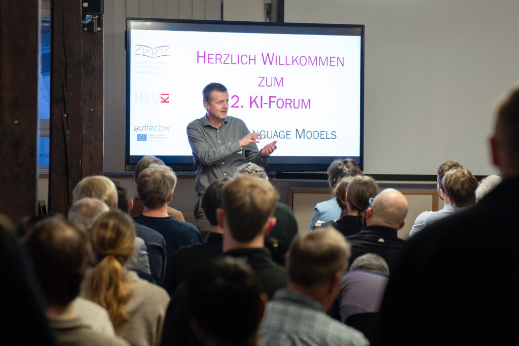 Begrüßungsvortrag beim 2. KI‑Forum vor einer Leinwand zum Thema Large Language Models.