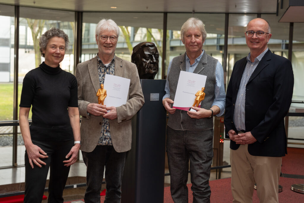 Alumni der HSU/UniBw H stehen mit Vizepräsidentin Univ.-Prof. Dr. Christina Schaefer und Vizepräsident Univ.-Prof. Dr. Thomas Klassen vor der Helmut-Schmidt-Statue der Universität. 