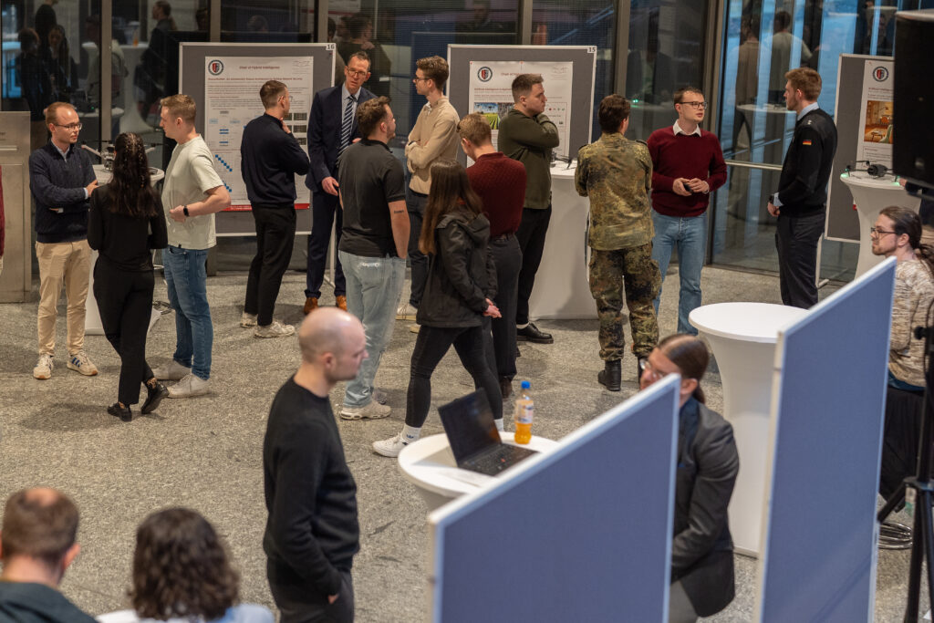 Belebte Posterpräsentation mit mehreren Gesprächsgruppen in einem großen Foyer.