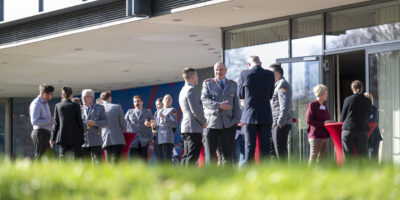 Menschen in Uniformen stehen im vor einem Gebäude und Unterhalten sich.