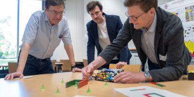 Mehrere Teilnehmende arbeiten gemeinsam an einem elektronischen Aufbau während eines Workshops.