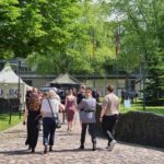 Mehrere Besucher gehen über einen Weg zwischen Gebäuden und Veranstaltungsständen auf dem Campus.