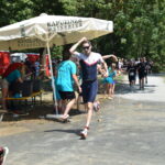 Triathlet läuft bei hoher Sommerhitze auf der Laufstrecke der Deutschen Hochschulmeisterschaft im Triathlon an einer Verpflegungsstation vorbei.