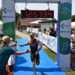 Triathlet überquert die Ziellinie eines Wettkampfs.
